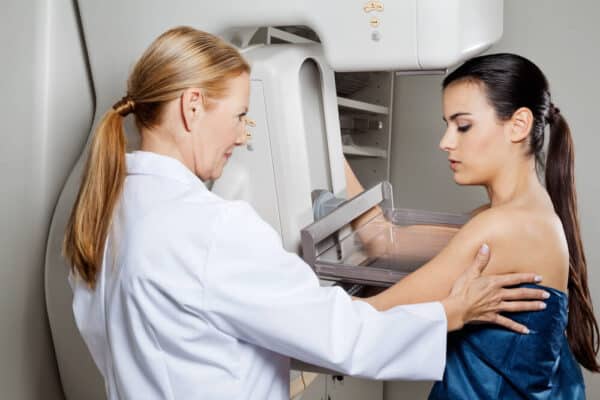  A female doctor assists a female patient with a mammogram.