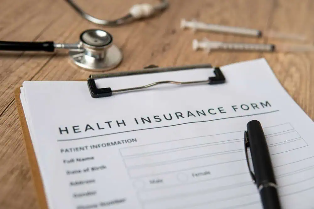 A health insurance form on a table with a stethoscope and medical supplies
