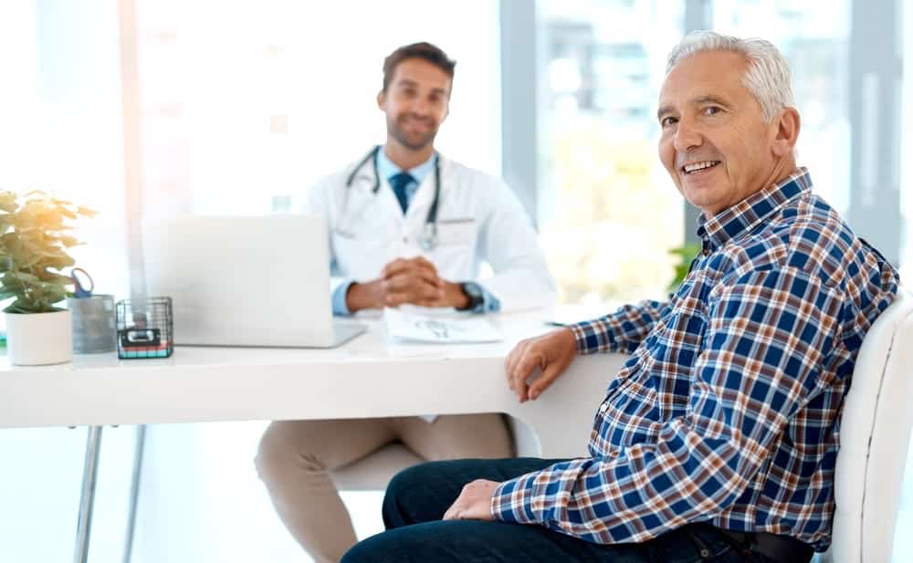A happy elderly patient consulting with his doctor