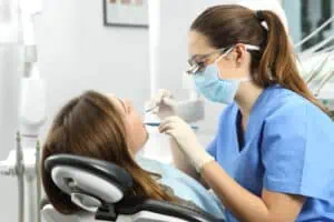 A dental hygienist performing a teeth cleaning on a woman