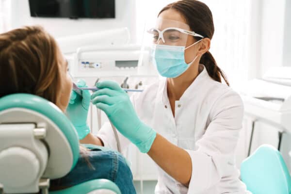 A smiling female dentist conducting a dental exam on a pediatric patient