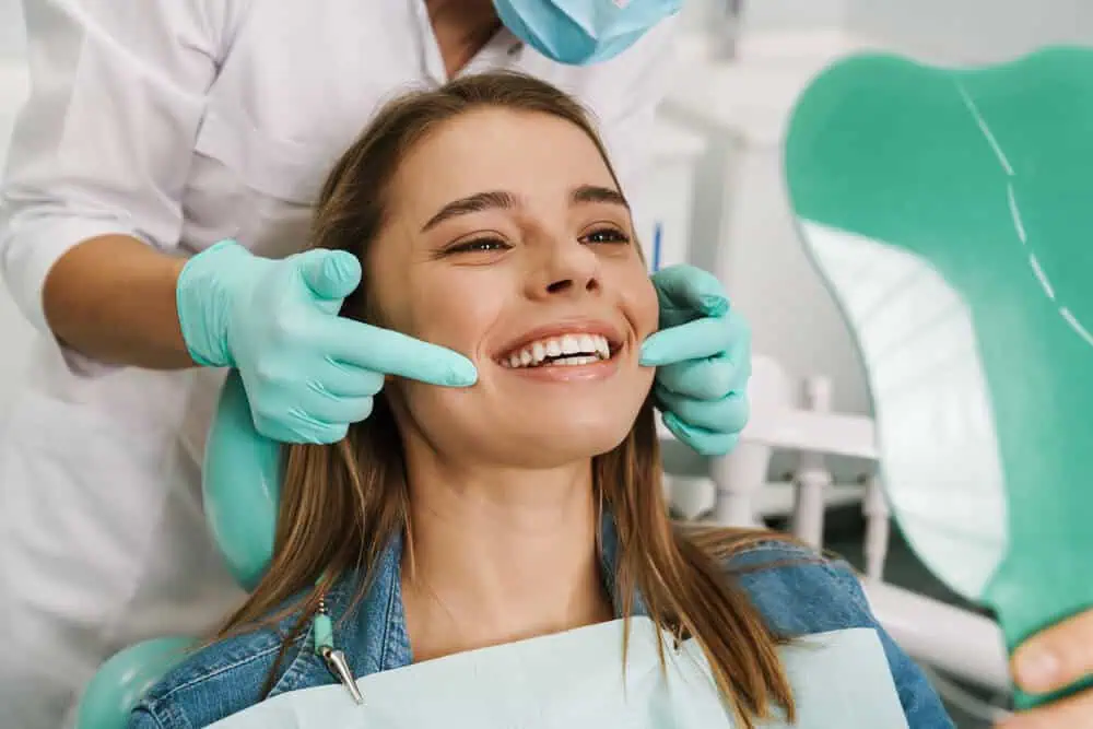 A female patient in a dental chair smiling during a dental exam