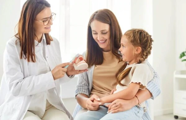 Mother and girl attend an appointment with a dentist doctor or nurse to learn about tooth cleaning.